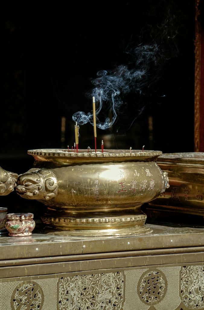 A golden incense burner releasing smoke in a Ho Chi Minh City pagoda, Vietnam.